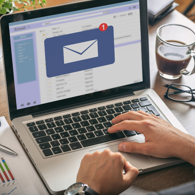 Person using a laptop with an email automation notification on screen.