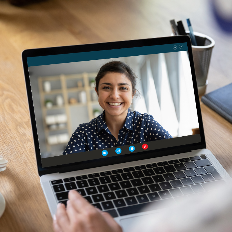 Smiling woman on a laptop screen during a secure virtual session, representing client access through a HIPAA-compliant portal.