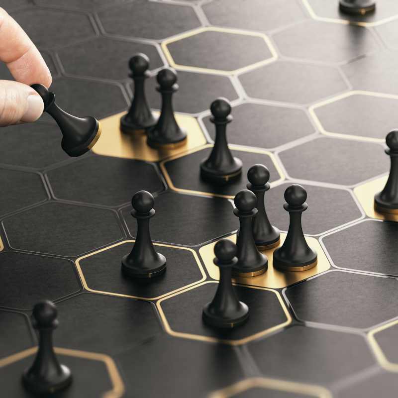 Target audience concept shown with a hand strategically placing chess pawns on a black and gold hexagonal board.