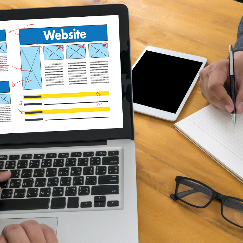 Website wireframe design on a laptop screen with notes for improving layout and boosting online conversions.